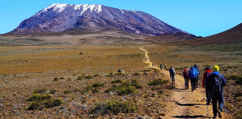 Group of climbers ascending a wide alpine plateau toward Kilimanjaro